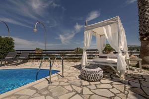 a bed and a canopy next to a swimming pool at Villa Emma in Gerani