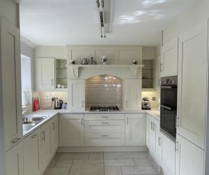 uma cozinha com armários brancos e um forno com placa de fogão em Bar View House em Newry