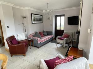 a living room with a couch and chairs and a tv at Bar View House in Newry