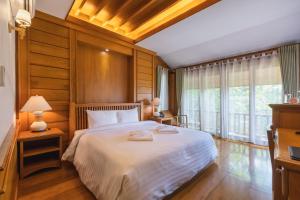 來興的住宿－Vanasin Residence，一间卧室配有一张带木墙的大床