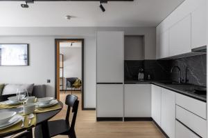 a kitchen and dining room with a table and a kitchen with white cabinets at Balcia Residence in Riga