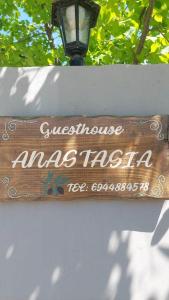 a wooden sign on a white fence with a street light at ANASTASIA in Makri