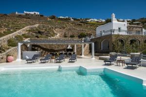 una piscina con sillas, una mesa y una casa en Villa Jet by Mykonos Rocks, en Mykonos ciudad