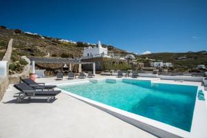 a man sitting in a chair next to a swimming pool at Villa Jet by Mykonos Rocks in Mikonos