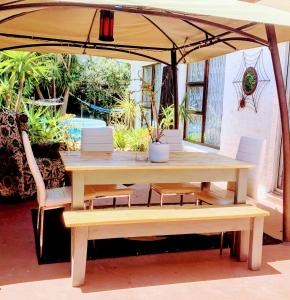 una mesa de madera y bancos bajo una sombrilla en Regent Casa’s, en Ciudad del Cabo