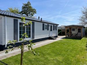 a small white house with a yard at De Roos chalet 174 in Sint Annaland