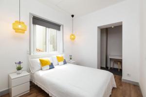 biała sypialnia z białym łóżkiem z żółtymi poduszkami w obiekcie Minimalist Apartment In Caldas w mieście Caldas da Rainha
