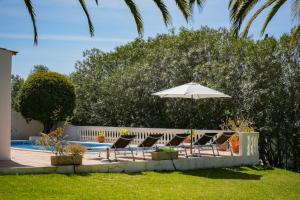 eine Gruppe Stühle und ein Sonnenschirm neben einem Pool in der Unterkunft Casa Luzerna in Carvoeiro