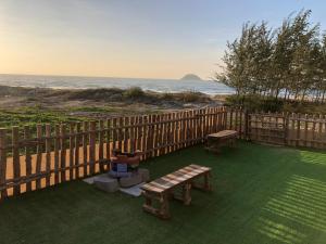 ラジーにあるLagi Retreat homestay Home ngay mặt biển Lagiの浜辺の芝生に座るベンチ2つ