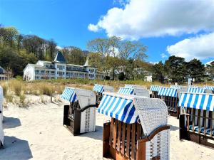 eine Reihe von Stühlen am Strand mit einem Haus im Hintergrund in der Unterkunft Seeschloss Binz 24 in Binz