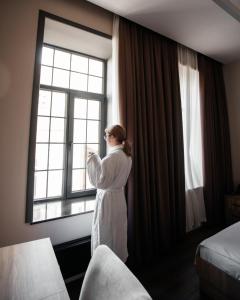 a woman standing in a hotel room looking out the window at OLF Hotel in Baku