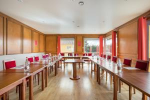 a large room with wooden tables and red chairs at H&ocirc;tel Newport in Villefranche-sur-Sa&ocirc;ne