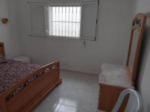 Habitación pequeña con cama y ventana en Confortable Maisonnette prés de la plage à Dar el Alouch, en Kelibia