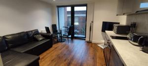 a living room with a black couch and a kitchen at Earl Street 122 in Sheffield