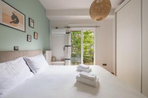 - une chambre avec un grand lit blanc et des serviettes dans l'établissement Confy Living Apartment Metaxourghio Metro Station, à Athènes