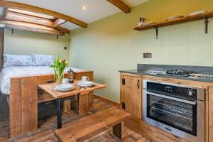a kitchen with a table and a bed in a room at Bertha Shepherd's Hut in Lydney