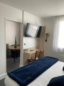 a bedroom with a bed and a desk with a television at Hôtel Le Goëlo - Port de Paimpol in Paimpol