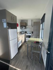 a kitchen with a refrigerator and a table in it at Amberlea Cottages in Hokitika