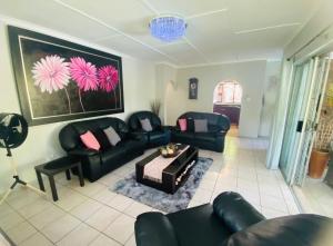 a living room with black leather couches and a table at Pelican's Nest Holiday Home St Lucia in St Lucia