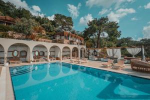 a swimming pool with chaise lounge chairs and a resort at Zakros Hotel Lykia in Faralya