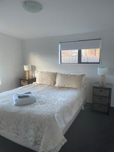 a bedroom with a white bed with two lamps and a window at Amberlea Cottages in Hokitika