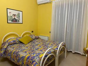 ein Schlafzimmer mit einem Bett mit einer Bettdecke und einem Fenster in der Unterkunft The Orange House in Assemini