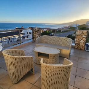 un patio con mesa, sillas y el océano en JONGENSFONTEIN, en Jongensfontein