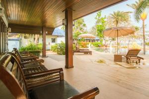 a patio with benches and an umbrella and a pool at Rocky Point Resort in Thap Sakae