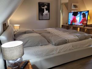 ein großes weißes Bett im Wohnzimmer mit TV in der Unterkunft Ferienwohnung 9 in der Waldstraße 23 in Sankt Peter-Ording