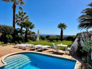 una piscina con mesa, sillas y palmeras en Casa Eureca, en Carvoeiro