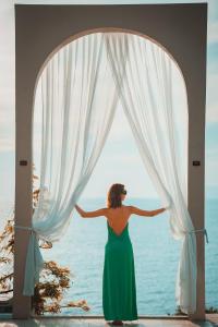 a woman in a green dress looking out of a window at Zakros Hotel Lykia in Faralya