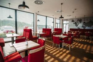 un restaurante con sillas rojas, mesas y ventanas en Pension JASOPA, en Pardubice