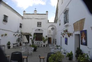 dziedziniec białego budynku ze stołami i krzesłami w obiekcie Casa Rural Las Cadenas del Cananeo w mieście Arcos de la Frontera