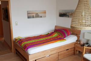 Una cama con una manta de colores encima. en 3-Room Apartment in Rowhouse - Oktoberfest, Trade Shows, Business, en Maisach