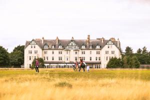 a group of people flying kites in front of a large building at Dornoch Station in Dornoch