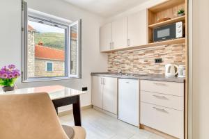 a kitchen with white cabinets and a table and a window at Symphony Apartments Street View in Petrovac na Moru