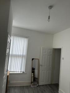 een kamer met een raam, een spiegel en een deur bij Muram Properties in Kirkby