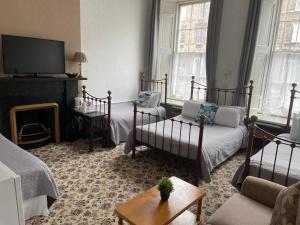 een woonkamer met 2 bedden en een televisie bij Atlas Guest House in Edinburgh