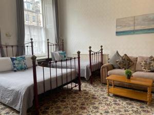 Atlas Guest House في إدنبرة: غرفة نوم بسريرين واريكة
