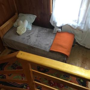 a small bed in a room with a wooden floor at Cabana Trei Brazi Dambovita in Bezdead