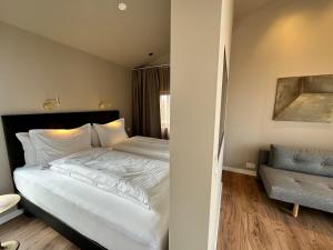 a bedroom with a large white bed and a chair at Urriðafoss Waterfall Lodges in Selfoss