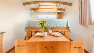 利德尼的住宿－Betty Shepherd's Hut，一张带两个盘子和鲜花的小木桌