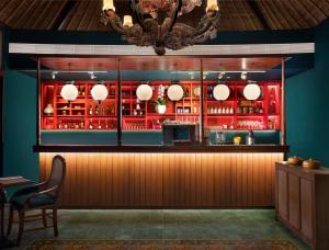a restaurant with a bar with red cabinets and a chandelier at Sudamala Resort, Sanur, Bali in Sanur