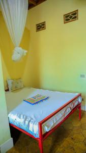 uma cama num quarto com uma parede amarela em Maison d'Accueil - Fondation San Filippo Neri em Bujumbura