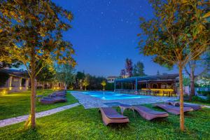 a swimming pool with lounge chairs in a yard at night at Folies Corfu Town Hotel Apartments in Corfu Town
