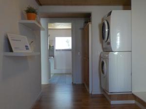 eine Küche mit einem Kühlschrank, einer Waschmaschine und einem Trockner in der Unterkunft Lyngsasgaard M in Sæby