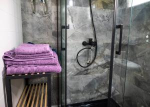 ein Badezimmer mit einer Dusche und lila Handtüchern auf einer Bank in der Unterkunft Tiny Villa among the olives in Iraklio