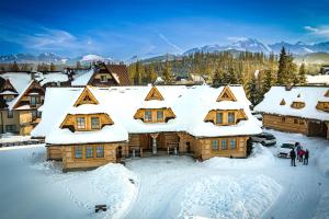 Cabaña de madera con nieve en el techo en Tatrzański Bór Apartamenty, en Małe Ciche