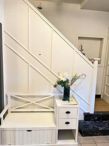 una escalera blanca con un jarrón de flores sobre una mesa en Cosy maison, en Oupeye