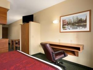 um quarto de hotel com uma secretária e uma cadeira em Days Inn & Suites by Wyndham Lafayette IN em Lafayette